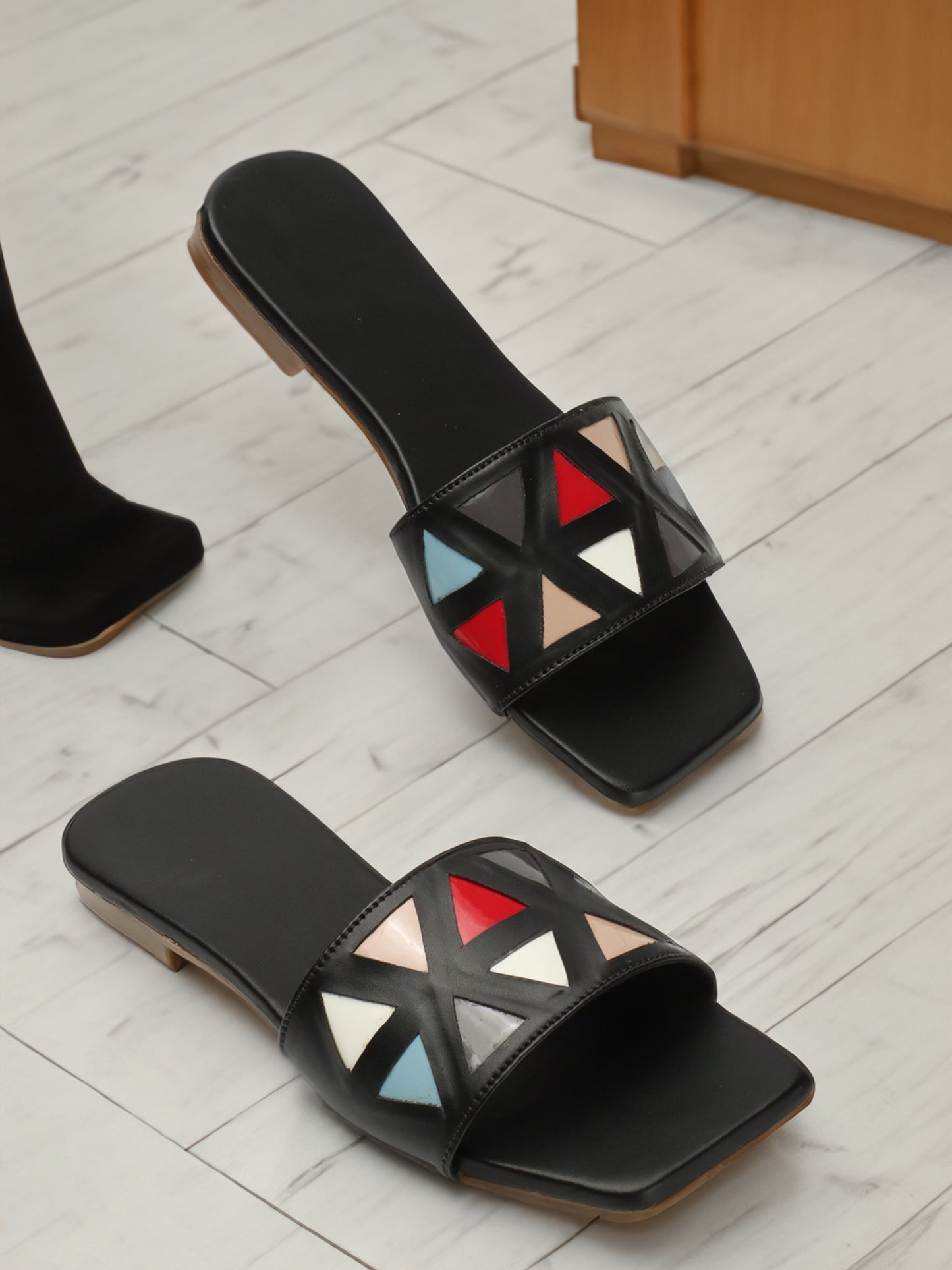 Chic black flat, vibrant triangle design atop. Modern elegance